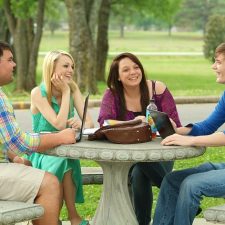 Students having a discussion in the green areas of campus.